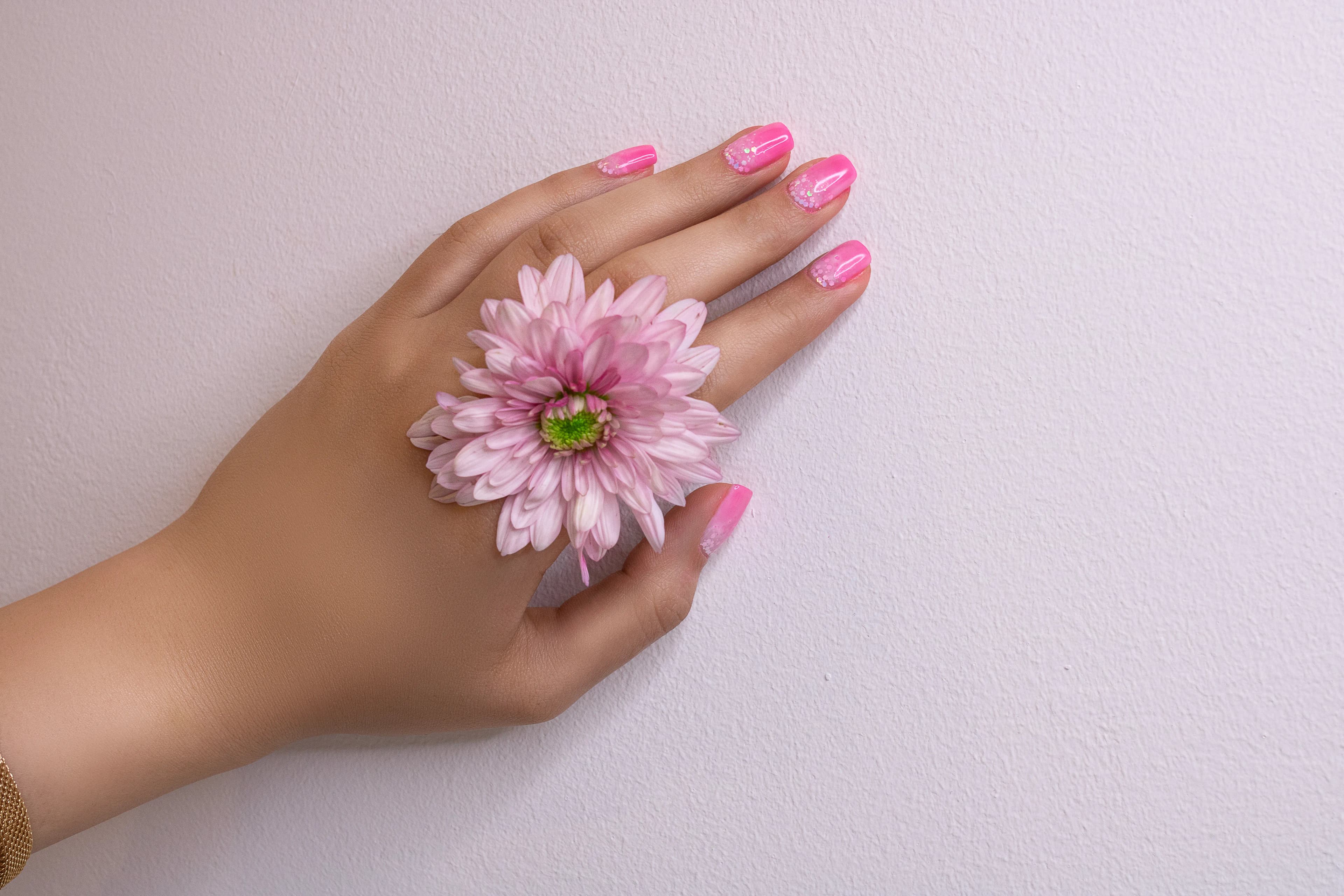 Unhas rosa claro segurando flor